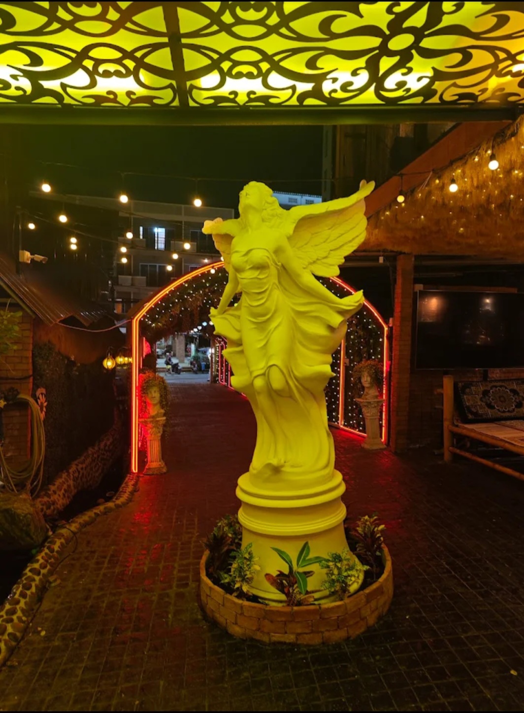 Decorative angel statue illuminated at night near the garden entrance