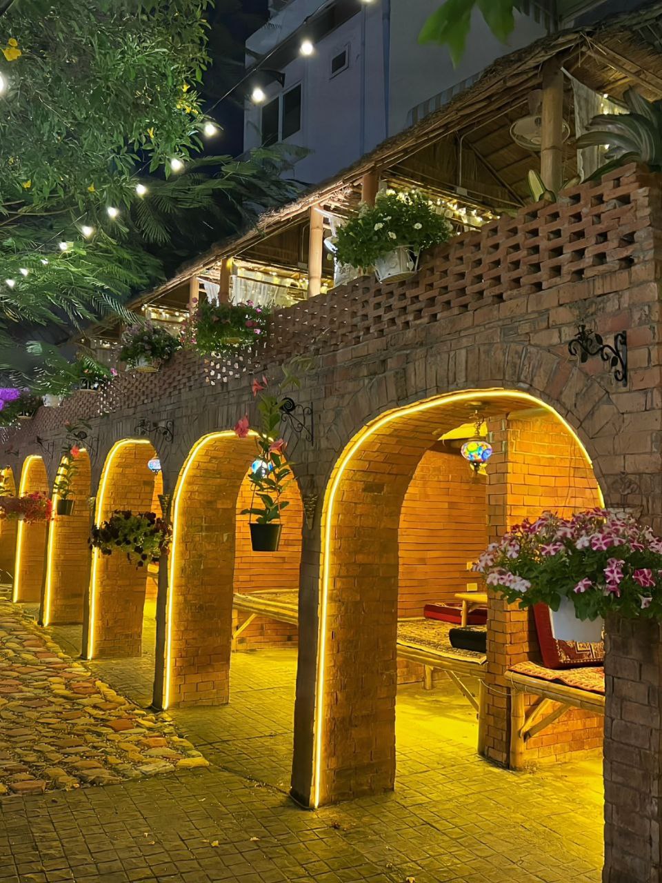 Beautiful illuminated brick arches with hanging flower baskets in the Q Garden dining area