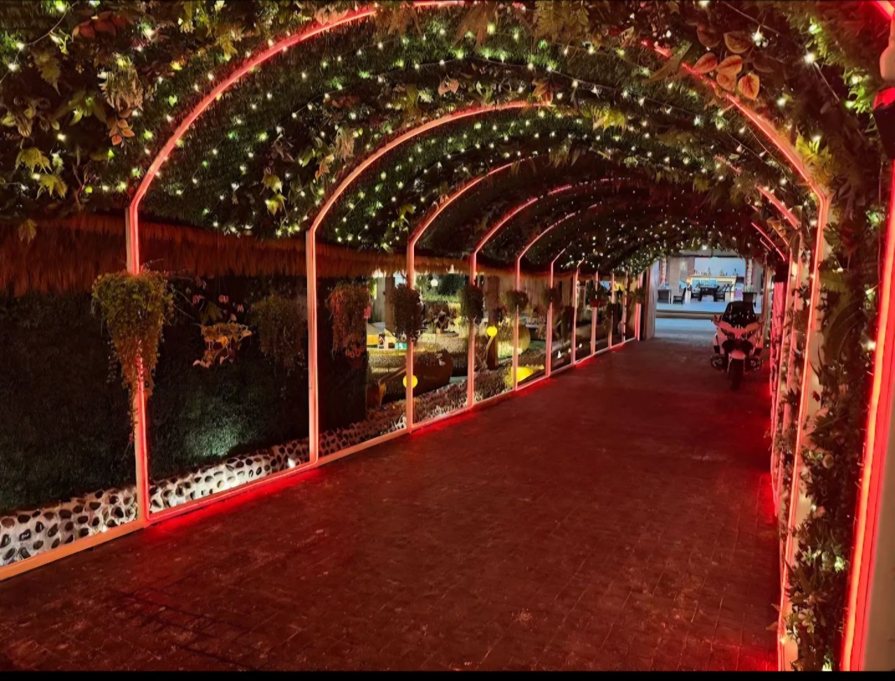 Enchanting red-lit garden entrance tunnel with lush greenery