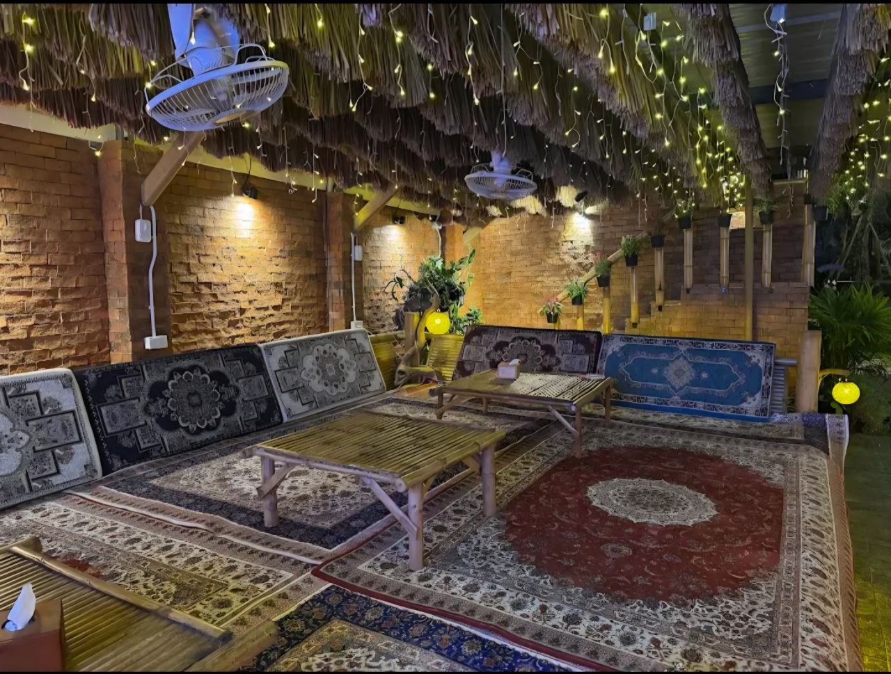 Cozy indoor seating area with cushions and ornate carpets under a thatched roof