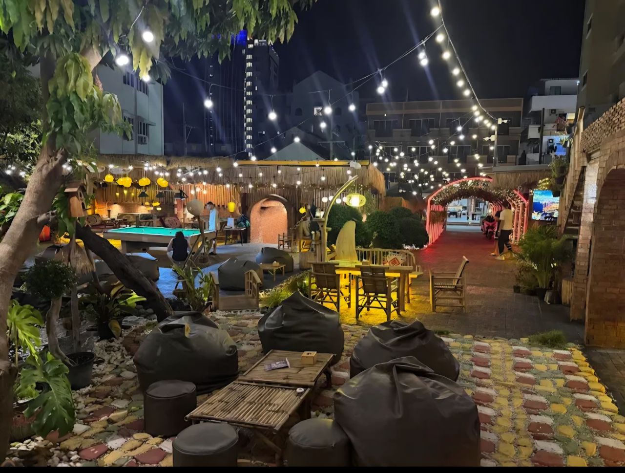 Q Garden outdoor area with bean bags, pool table, and string lights at night