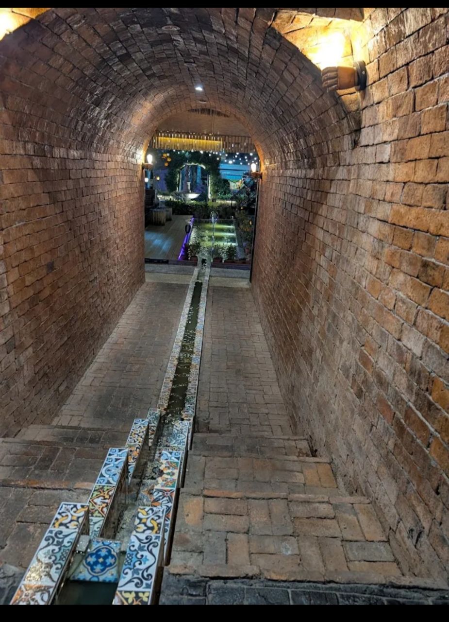 Atmospheric brick tunnel entrance with water feature leading to the garden