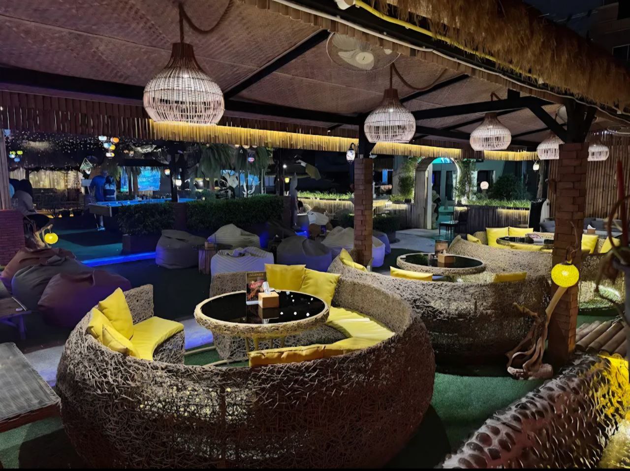 VIP lounge area with round stone seating, yellow cushions and hanging lanterns